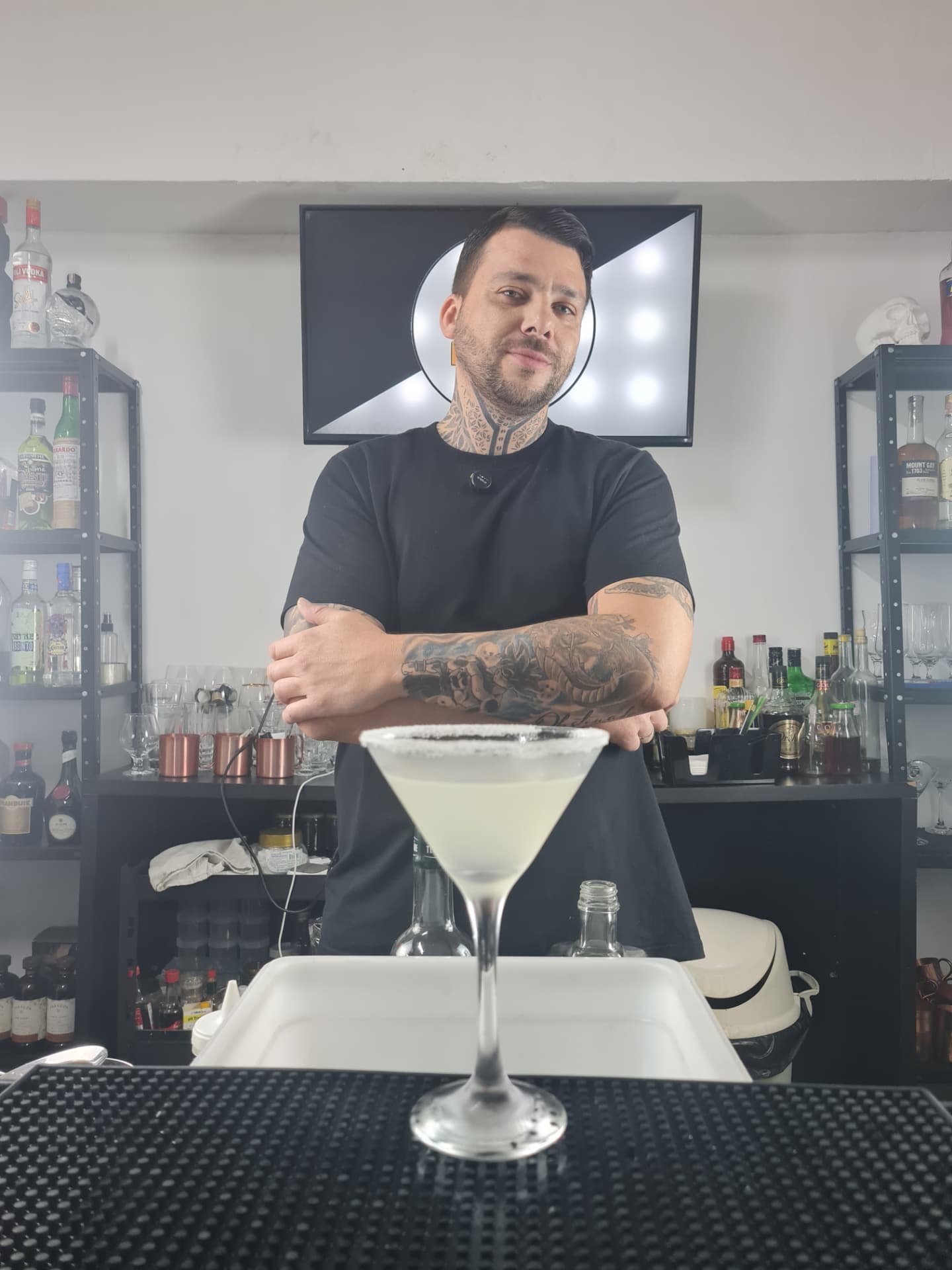 Instrutor da LuxBar atrás do balcão com um drink finalizado em taça