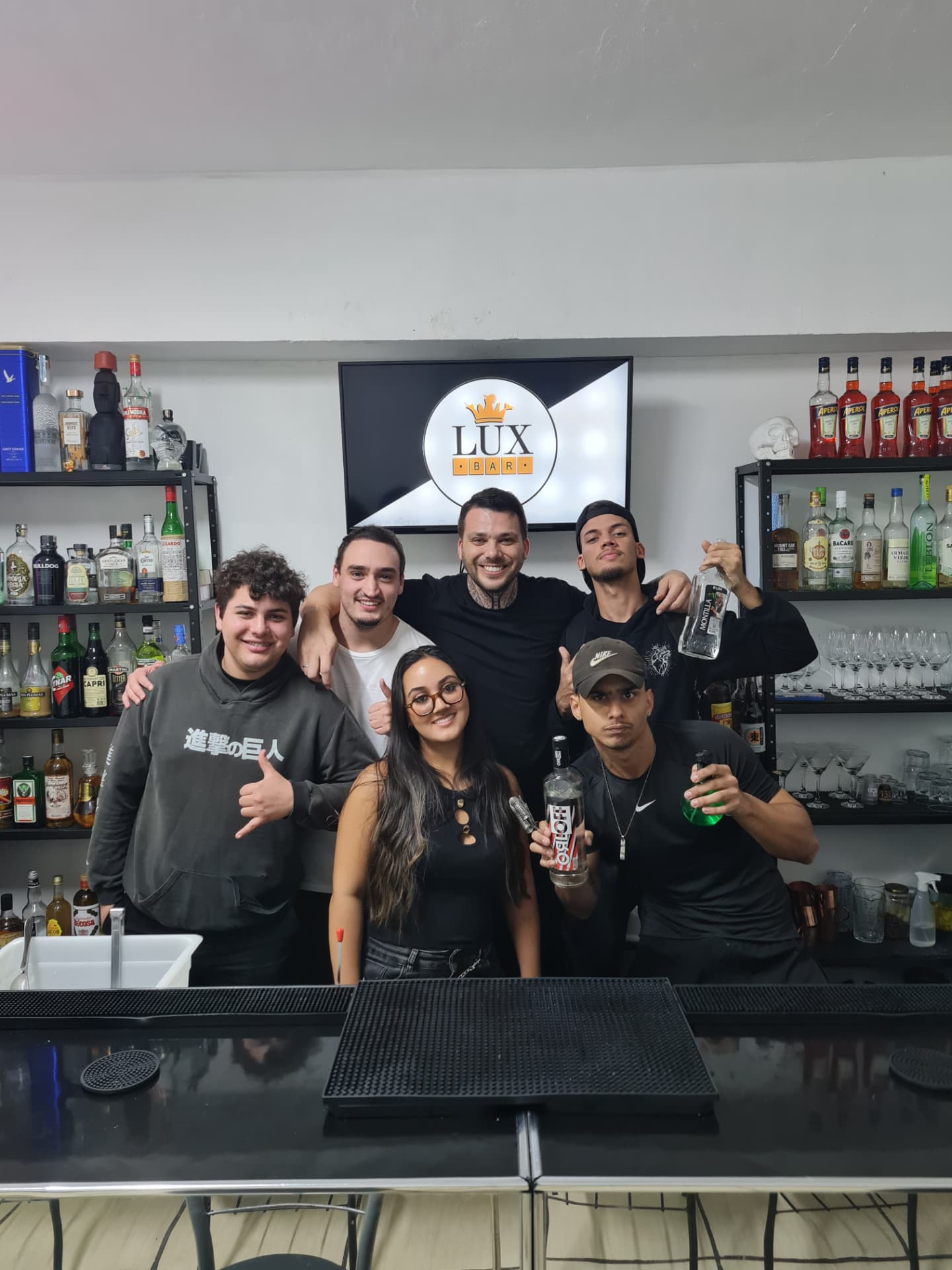 Alunos e instrutor durante aula prática com garrafas e utensílios de bar