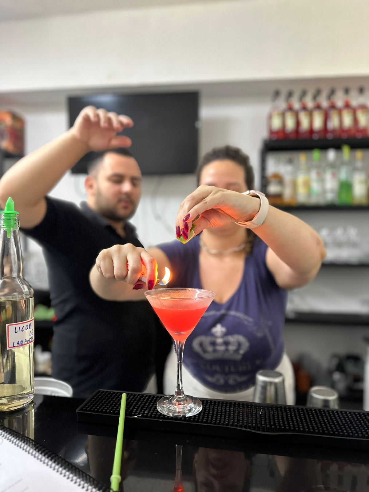 Aluna finalizando um coquetel com orientação do instrutor na LuxBar